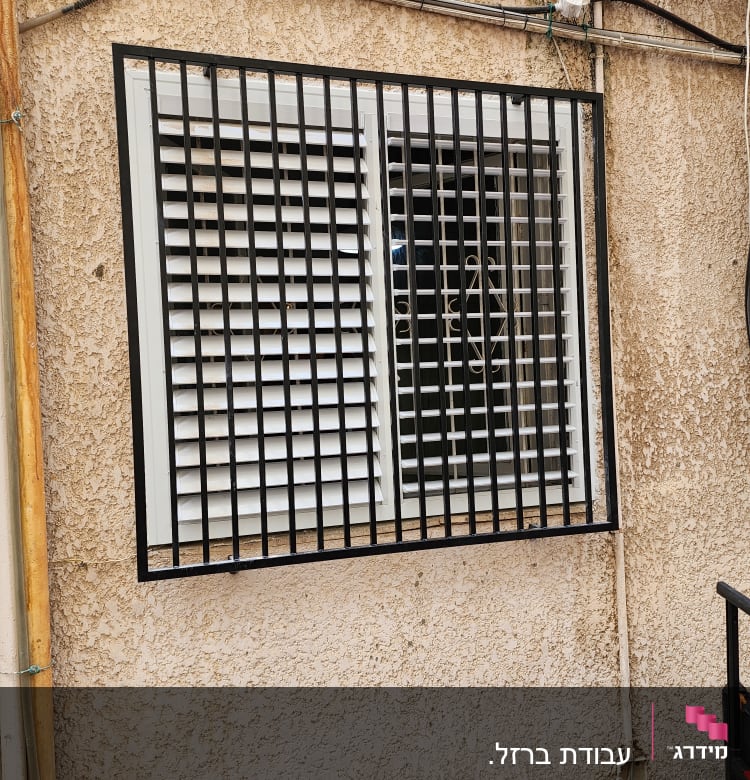 חלון עם תריסים וסורגים על קיר חיצוני